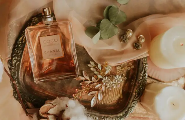 Flakon perfum Chanel Coco Mademoiselle, biżuteria i świece na ozdobnej tacy.