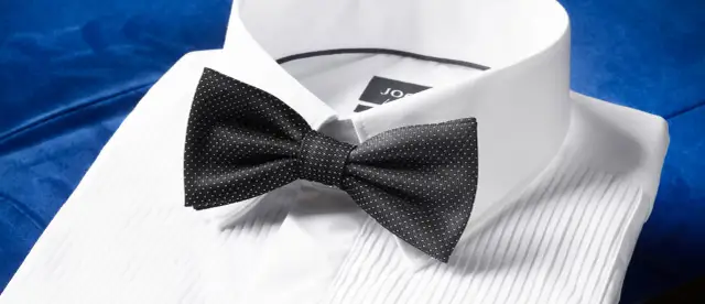 Czarna mucha w kropki na białej koszuli. Dowiedz się, jak założyć muchę, by wyglądać elegancko.