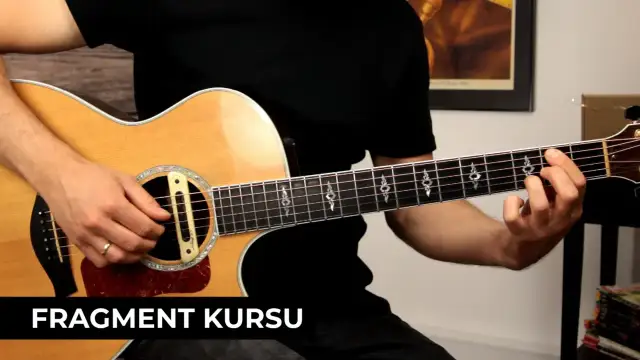 Dłoń grająca akord na gryfie gitary akustycznej.