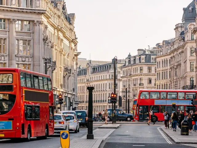 Londyńska ulica z czerwonymi autobusami piętrowymi i zabytkową architekturą.