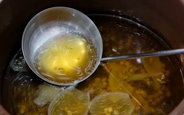 Nabierka z bulionem do grochówki, w garnku widać kawałki warzyw i przyprawy.