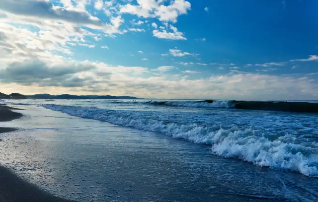 Plaża nad Bałtykiem z falami i błękitnym niebem z chmurami.