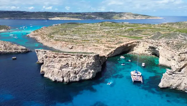 Malta, z jej malowniczymi zatokami i turkusową wodą, jest domem dla około 530 tys. mieszkańców. Widać tu łodzie i klify.