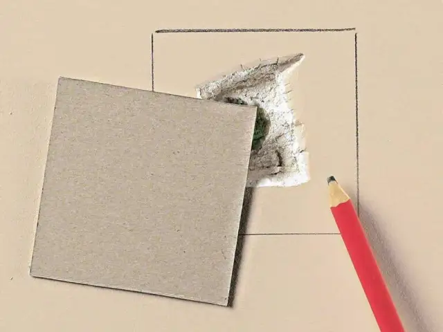 Kartonowy plaster i ołówek czekają, by pokazać, jak załatać dużą dziurę w ścianie.