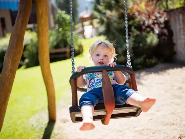 Niemowlę na huśtawce w ogrodzie.