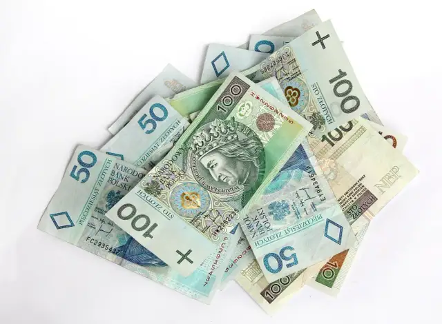 Stos banknotów 50 i 100 zł. Czy premia uznaniowa może pokryć koszty chorobowe?