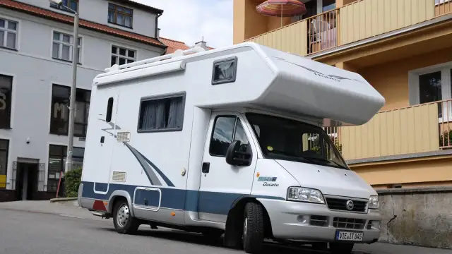 Biały kamper Fiat Ducato zaparkowany na ulicy. Zastanawiasz się, ile miejsc ma bus tego typu?