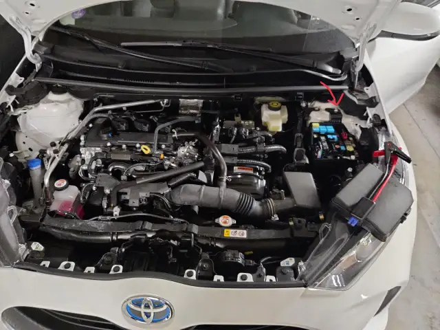 Silnik Toyoty Yaris Hybrid z widocznym skrzynką bezpieczników i klemami.