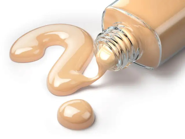 Krem podkładu wylewa się z butelki, tworząc kształt znaku zapytania.