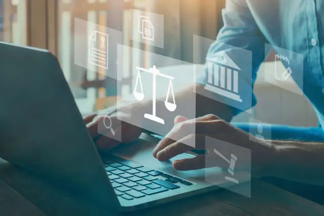 Dłonie piszące na laptopie, nad nimi ikony prawa: waga, budynek sądu, dokumenty.
