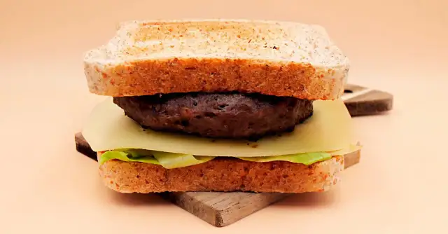 Burger z wołowiny, serem, sałatą i tostami na desce.