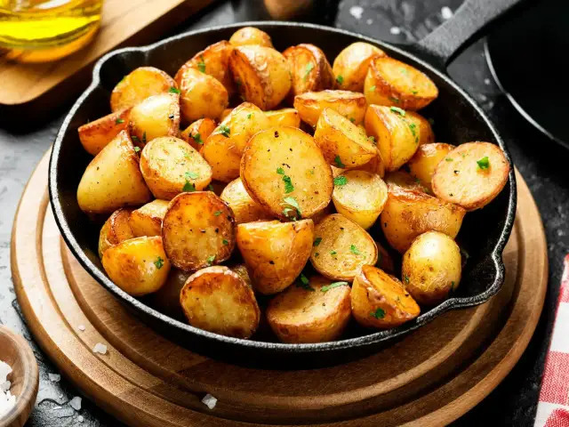 Chrupiące, złociste ziemniaczki usmażone na patelni, posypane natką pietruszki.