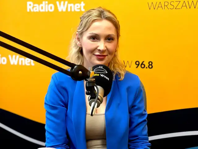 Joanna Miziołek, w wieku około 40 lat, w niebieskiej marynarce, udziela wywiadu w Radiu Wnet.
