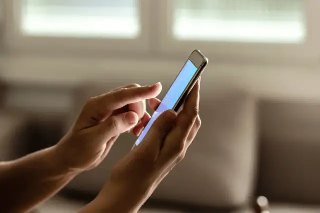 Dłonie trzymają smartfon, na którym można sprawdzić ile lat ma telefon.