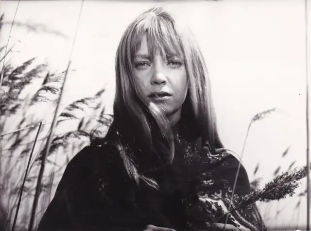 Irena Szczurowska w otoczeniu trzcin, zamyślona, z kosmykami włosów opadającymi na twarz.