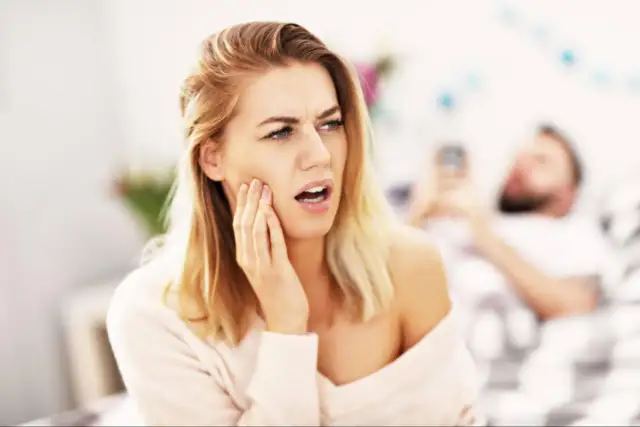 Kobieta z odrętwiałą twarzą po wizycie u dentysty.