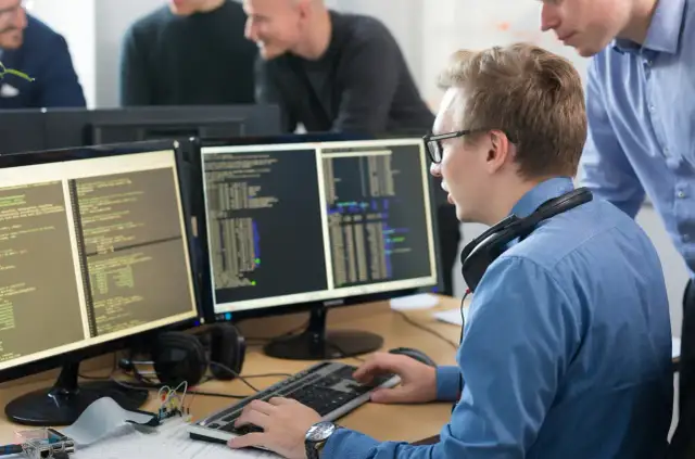 Programiści pracują nad kodem na monitorach, tworząc wolne oprogramowanie.