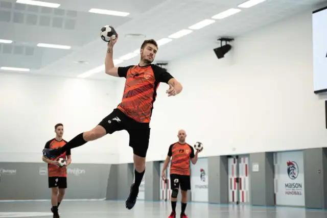 Gracz w skoku rzuca piłką ręczną. Kto wymyślił piłkę ręczną? Może ten zawodnik?