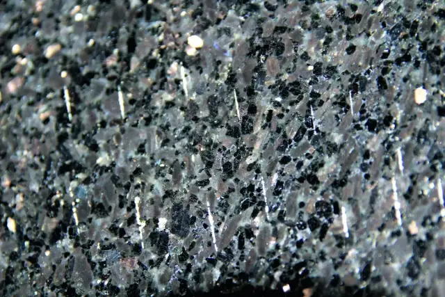 Zbliżenie na ciemny, granitowy blat kuchenny z widocznymi białymi, pionowymi rysami.