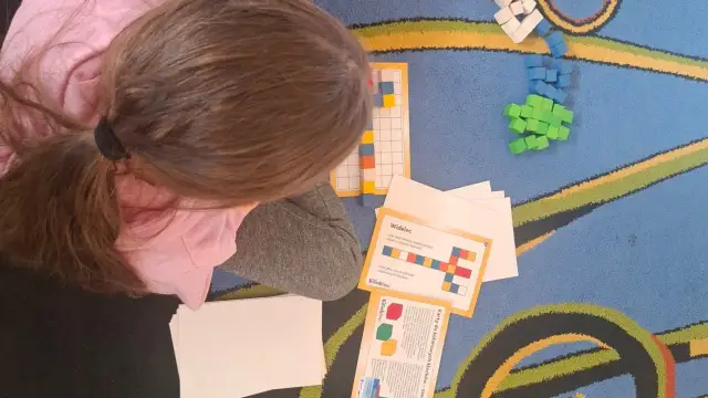 Dziecko układa kolorowe klocki według wzoru na karcie.