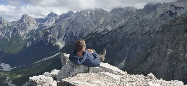 Mężczyzna odpoczywa na skale, podziwiając majestatyczne, skaliste góry przeklęte.