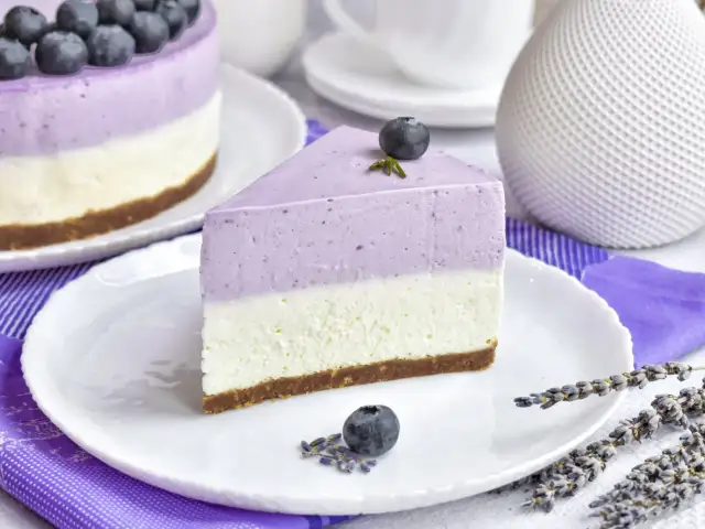 Pyszny sernik z jogurtu naturalnego z jagodami, udekorowany świeżymi owocami i lawendą. Idealny deser na każdą okazję.