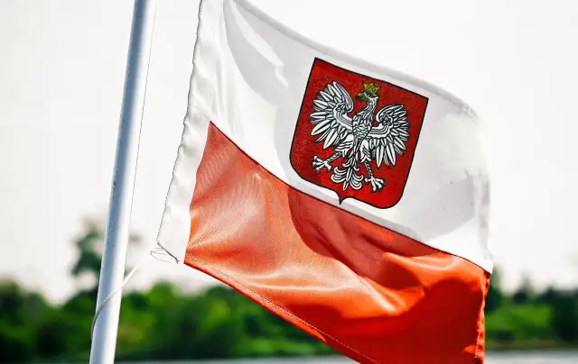 Flaga Polski z orłem, symbol wolności i niezależności. W tle zieleń, jak w kraju, gdzie zagraniczne banki w Polsce rozwijają skrzydła.