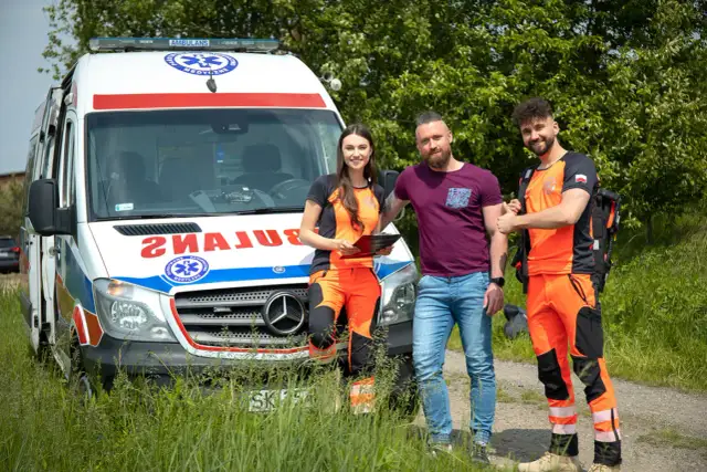 Trzech ratowników medycznych przy ambulansie. Zastanawiasz się, ile zarabia ratownik medyczny?