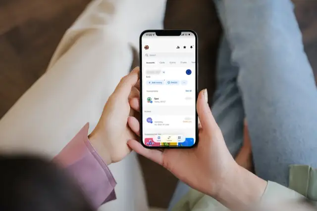 Osoba sprawdza transakcje na telefonie, widoczny jest debet na koncie Revolut po zakupach w Spar.