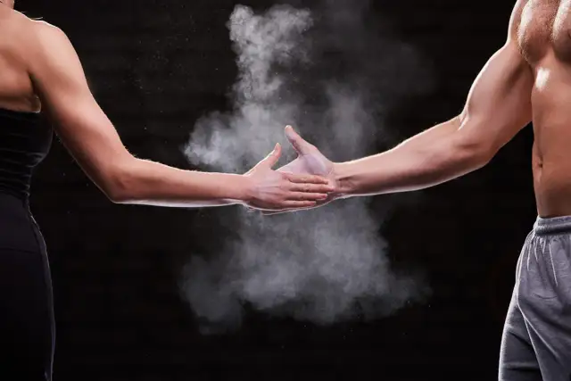 Dwie dłonie, męska i kobieca, spotykają się w chmurze magnezji. Pokazuje to siłę i determinację, cechy, które mogą być obecne u każdego, niezależnie od płci.