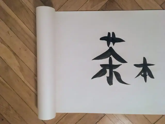 Chiński znak "herbata" namalowany tuszem na zwoju papieru, niczym legenda o herbacie.