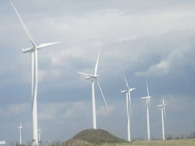 Wiatraki na tle pochmurnego nieba. Zastanawiasz się, ile wiatrak produkuje energii na godzinę?