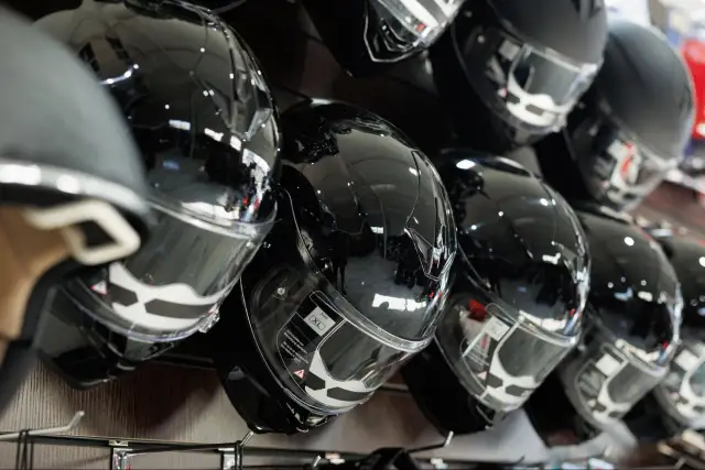 Błyszczące, czarne kaski motocyklowe na wystawie. Zastanawiasz się, jak dobrać kask motocyklowy? Wybierz idealny model dla siebie.
