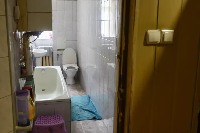 W łazience z wanną, toaletą i umywalką, widać, że lokal socjalny musi mieć łazienkę.