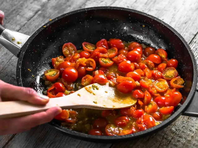 Gotowy do podania makaron z sosem pomidorowym. Pomidorki koktajlowe gotują się na patelni, tworząc pyszny sos.