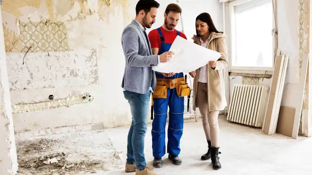 Inżynier, budowlaniec i klientka omawiają projekt. Zastanawiają się, co najpierw tynki czy wylewki, podczas remontu.