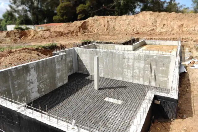 Bau einer Kellerbodenplatte mit Betonwänden und Bewehrung.