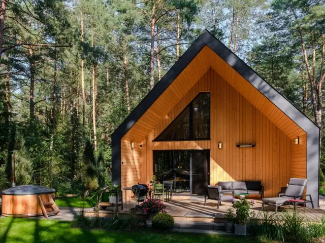 Drewniany dom szkieletowy w lesie z tarasem, jacuzzi i grillem.