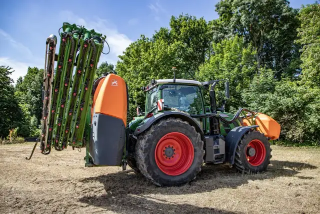 Zielony traktor z opryskiwaczem, gotowy do pracy w polu. Gdzie zrobić atest na opryskiwacz? Tutaj znajdziesz odpowiedzi.