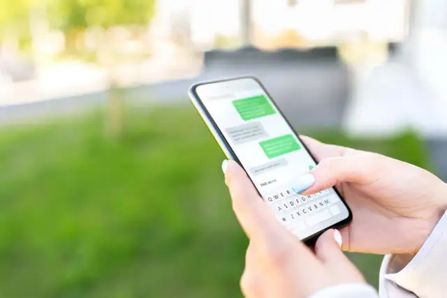 Dłoń trzyma smartfon z widoczną klawiaturą. Dowiedz się, jak przywrócić ustawienia klawiatury w telefonie, gdy coś pójdzie nie tak.