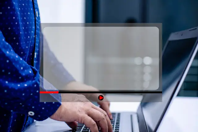 Osoba pisze na laptopie, a na ekranie widoczny jest odtwarzacz wideo. Dowiedz się, jak zmniejszyć ekran w przeglądarce, aby wygodniej oglądać.