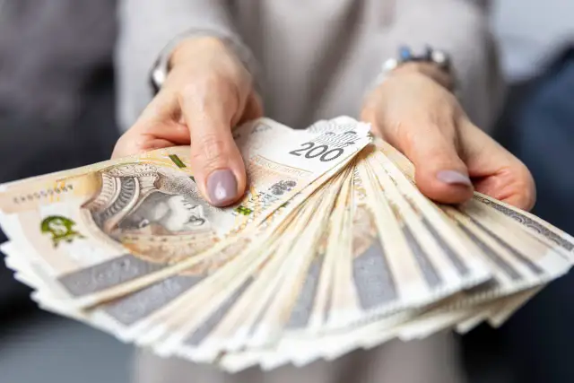 Dłonie trzymają wachlarz banknotów 200 zł. Zastanawiasz się, ile zarabia hotelarz?