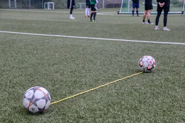 Dwa piłki na boisku połączone żółtą linką. Trening, który pokazuje, jak nie być profesjonalnym piłkarzem.