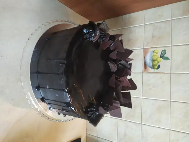 Czekoladowy tort z polewą, czekoladowymi płatkami i ciasteczkami Oreo.