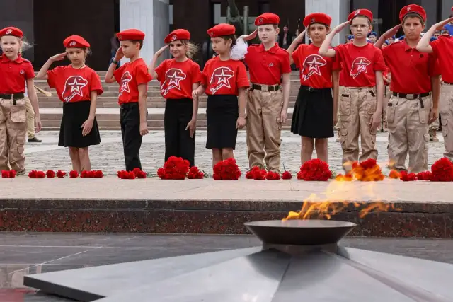 Dzieci w czerwonych beretach i koszulkach oddają hołd przy Wiecznym Ogniu. Utopijny i realny obraz rzeczywistości.