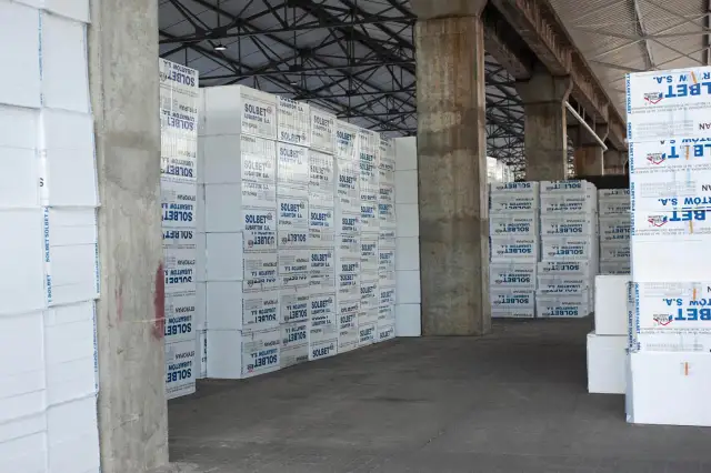 Stosy płyt styropianowych z nadrukiem "SOLBET LUBARTÓW S.A." w magazynie. Materiał budowlany o niskim współczynniku **styrobeton lambda**.