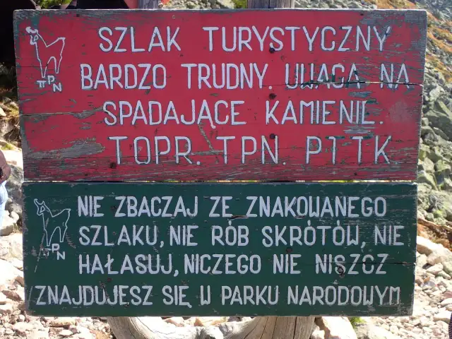 Tabliczka na szlaku turystycznym: "Bardzo trudny, uwaga na spadające kamienie". Niżej: "Nie zbaczaj ze szlaku, nie rób skrótów, nie hałasuj, niczego nie niszcz. Znajdujesz się w Parku Narodowym". Przełęcz Karb.