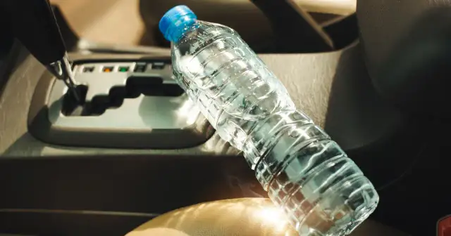 Butelka wody w samochodzie z tyłu, obok dźwigni zmiany biegów.