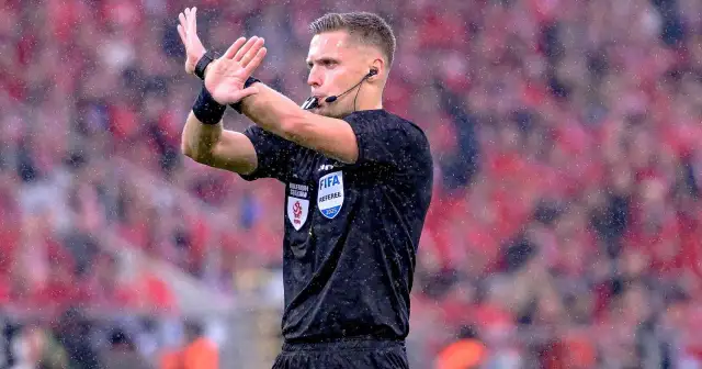 Sędzia w deszczu sygnalizuje decyzję. Ciekawe, ile zarabiają sędziowie w Lidze Mistrzów za takie emocje.