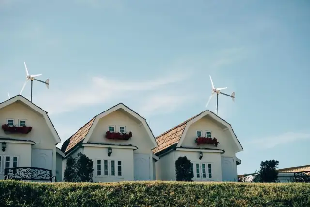 Domy z czerwonymi kwiatami i turbina wiatrowa bez pozwolenia na dachu.